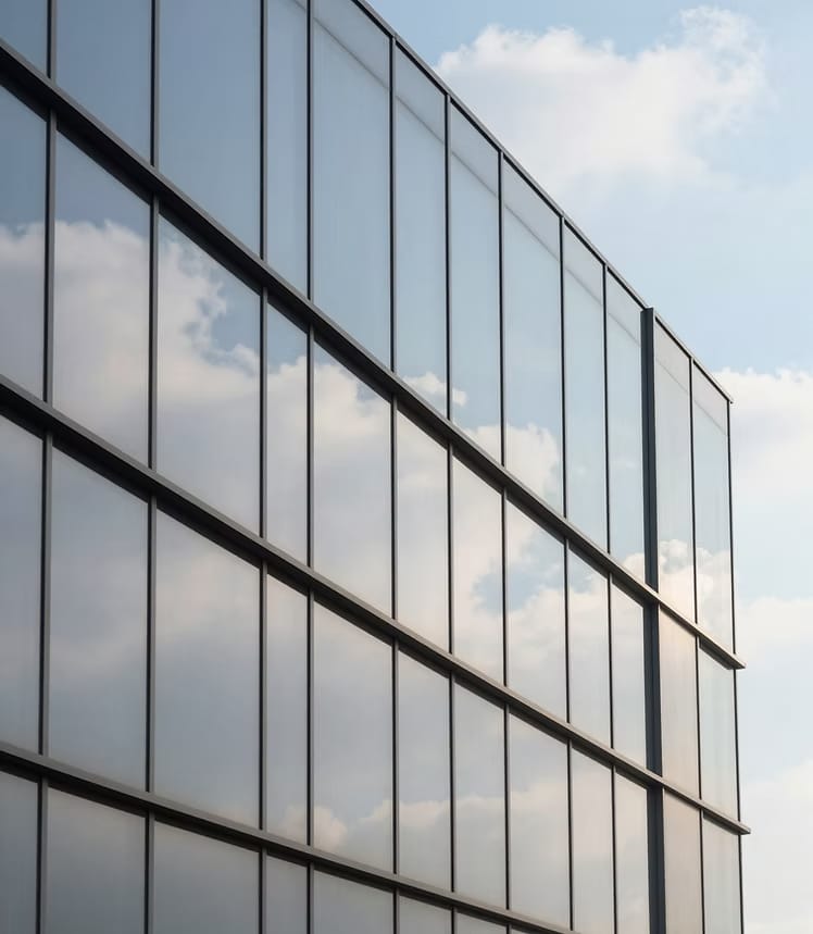 Fachada de edificio con muro cortina de vidrio reflejando el cielo